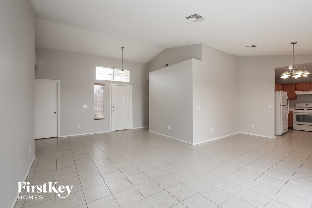 A spacious empty room with a kitchen area in the background.