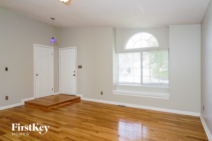 an empty living room with a window and wooden floors