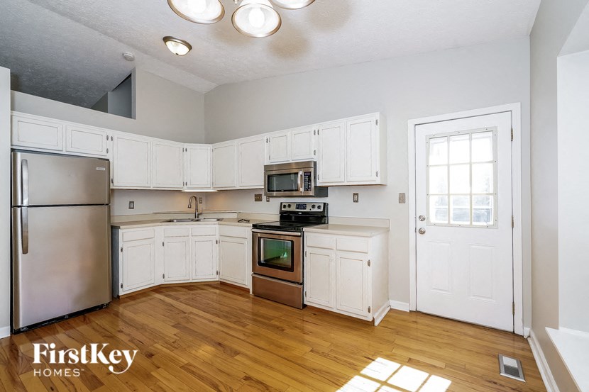 an empty kitchen with white cabinets and stainless steel appliances