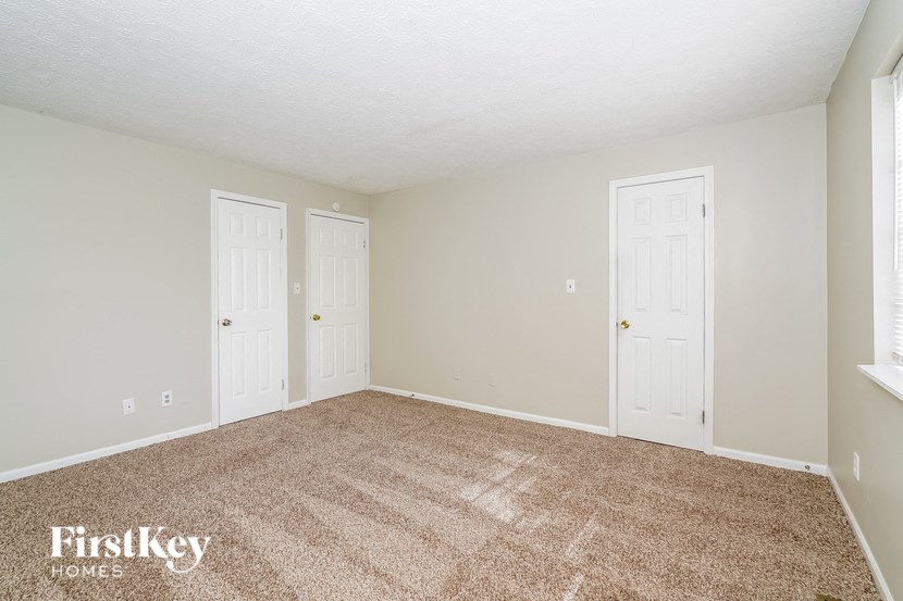the living room of a house with carpet and two doors