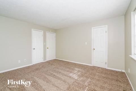 the living room of a house with carpet and two doors
