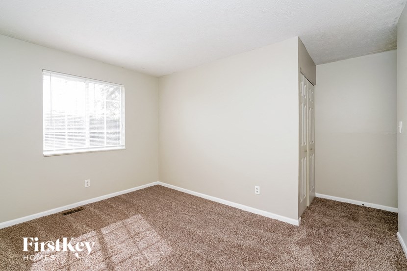 a bedroom with carpet and a window and a door