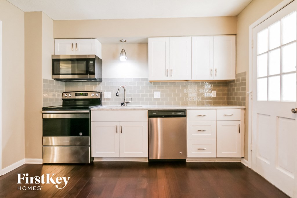 A kitchen with white cabinets and a stainless steel dishwasher and oven.