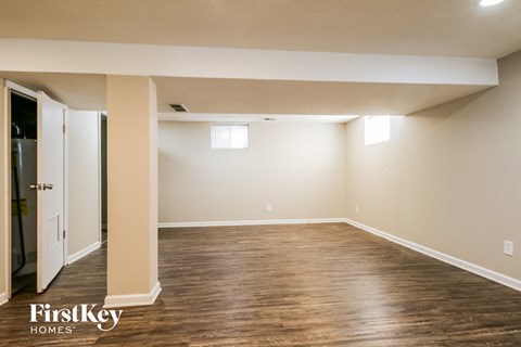 A spacious room with wooden floors and a doorway leading to another room.