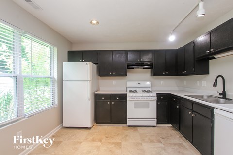 A kitchen with black cabinets and a white refrigerator.