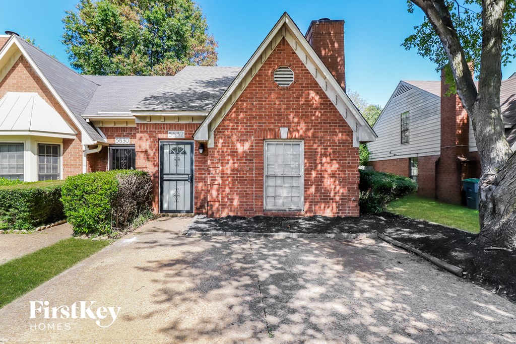 a brick house with a black door and a driveway