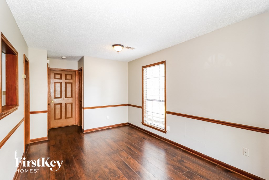 an empty living room with wood floors and white walls