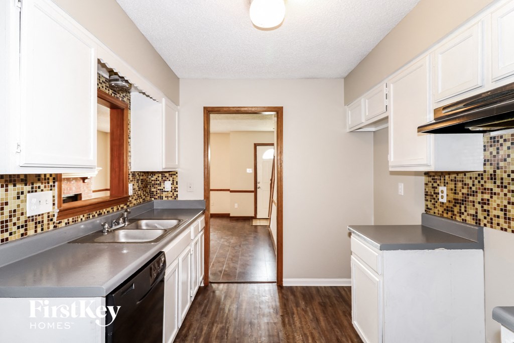 a kitchen with white cabinets and stainless steel appliances and a wood floor