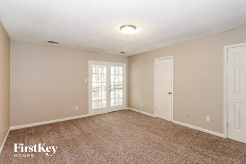 a spacious living room with carpet and two doors