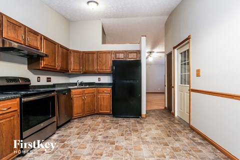 A kitchen with wooden cabinets and a black refrigerator.