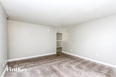 A spacious room with a carpeted floor and a door on the left side.