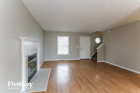 an empty living room with a fireplace and wooden floors