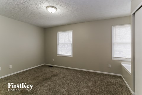 a bedroom with a carpeted floor and two windows