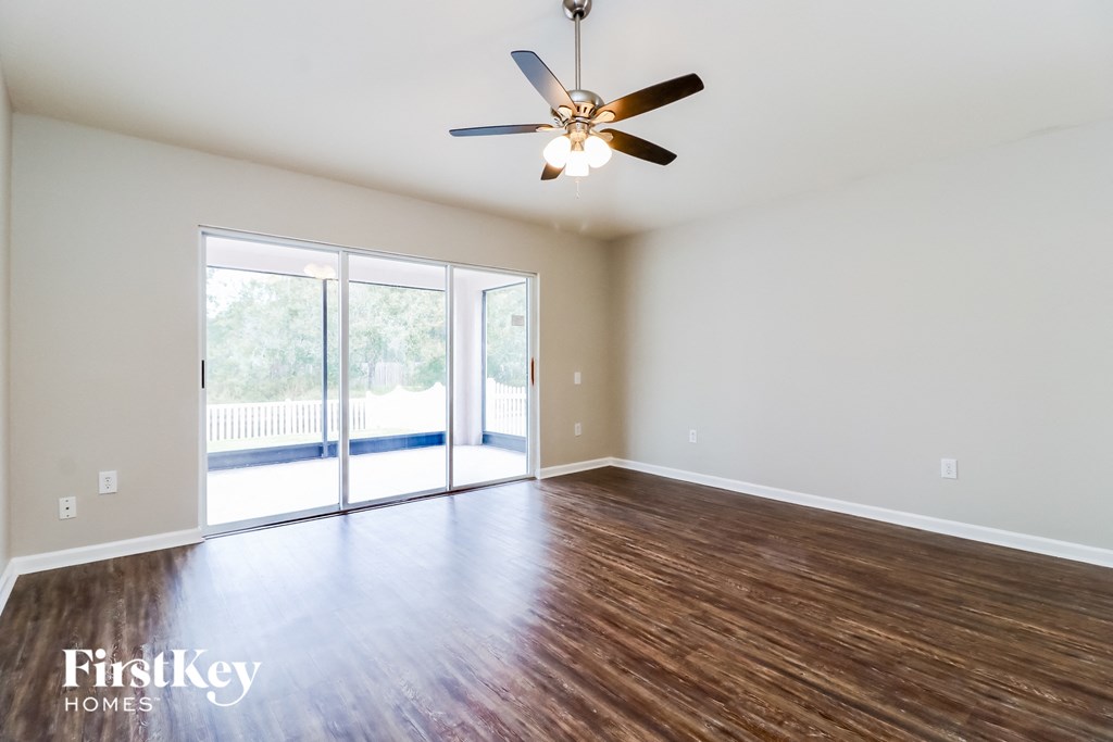 A room with a ceiling fan and sliding glass doors.