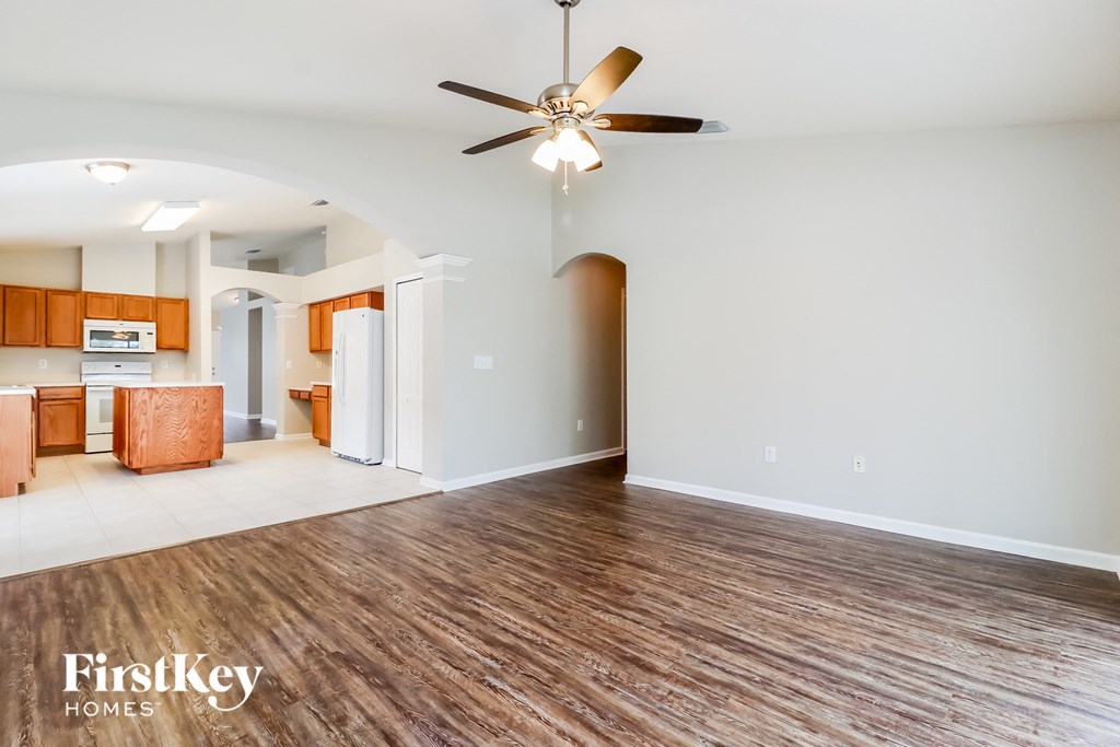 A spacious room with wooden flooring and a ceiling fan.