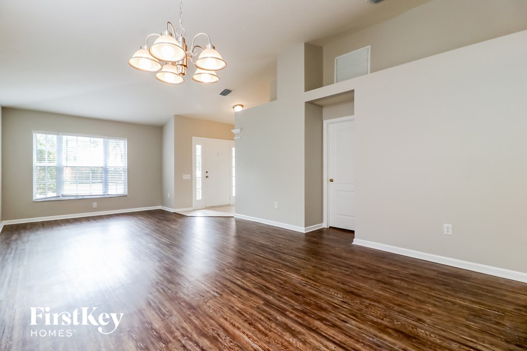 A spacious room with wooden floors and a large window.