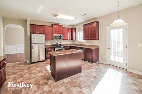 A kitchen with a refrigerator, microwave, and oven.