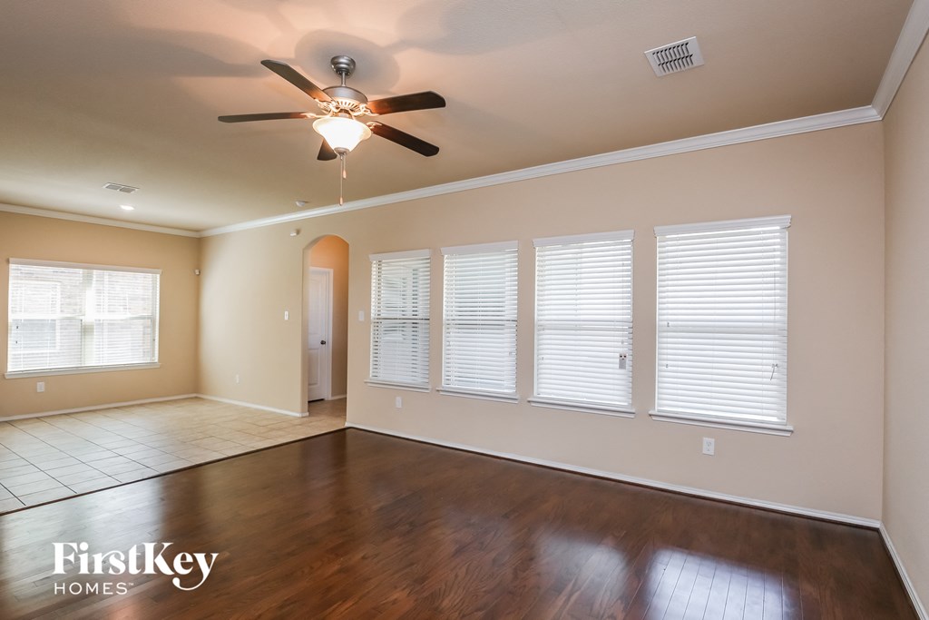 an empty living room with a ceiling fan and windows