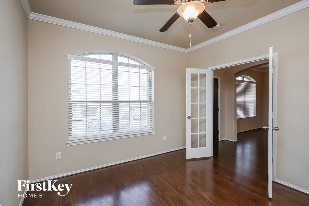 an empty living room with a ceiling fan and a window