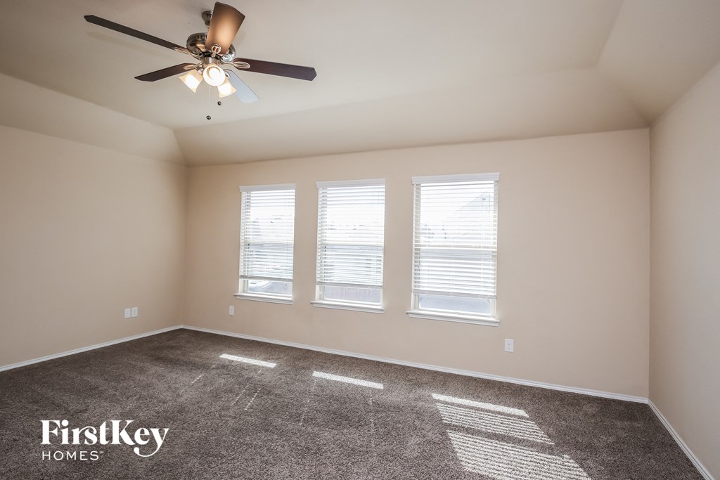 an empty room with a ceiling fan and three windows