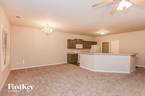 A spacious room with a fan and a kitchenette.