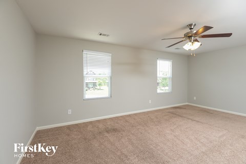 a living room with a ceiling fan and a carpet