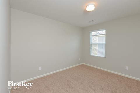 a bedroom with white walls and carpet and a window