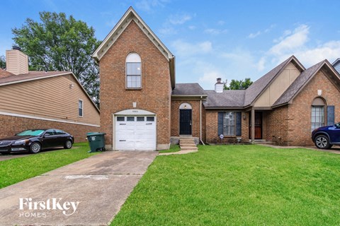 a brick home with a white garage door and a lawn