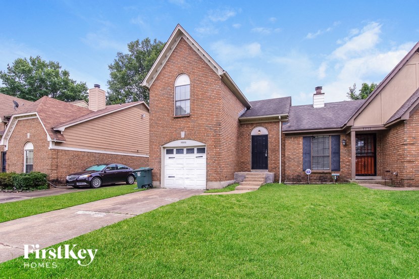 a brick home with a white garage door and a lawn
