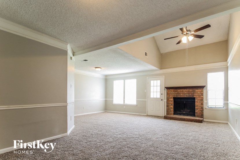 an empty living room with a fireplace and a ceiling fan