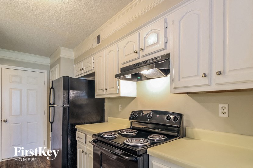 a kitchen with white cabinets and black appliances