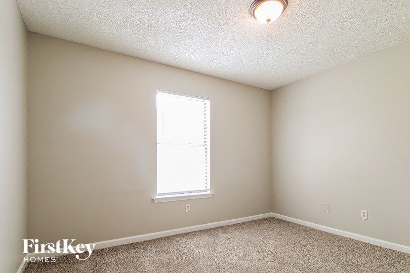 a bedroom with a window and a carpeted floor