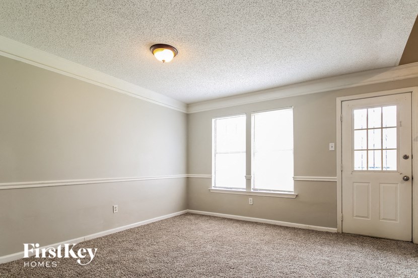 the dining room of an empty house with a door and window