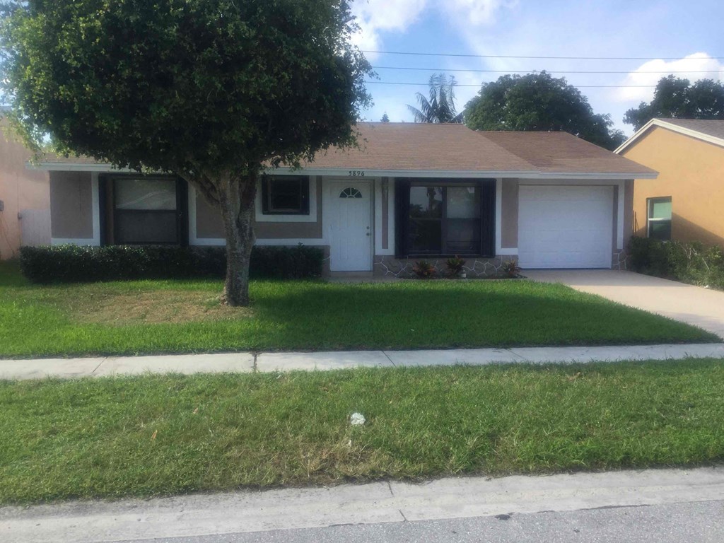 A house with a white garage door and a tree in front.