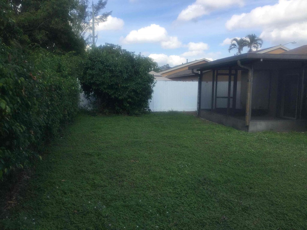A backyard with a house and a green lawn.