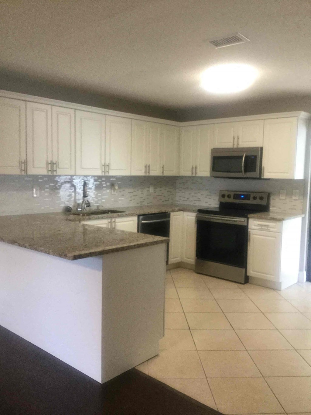 A kitchen with white cabinets and a granite counter.