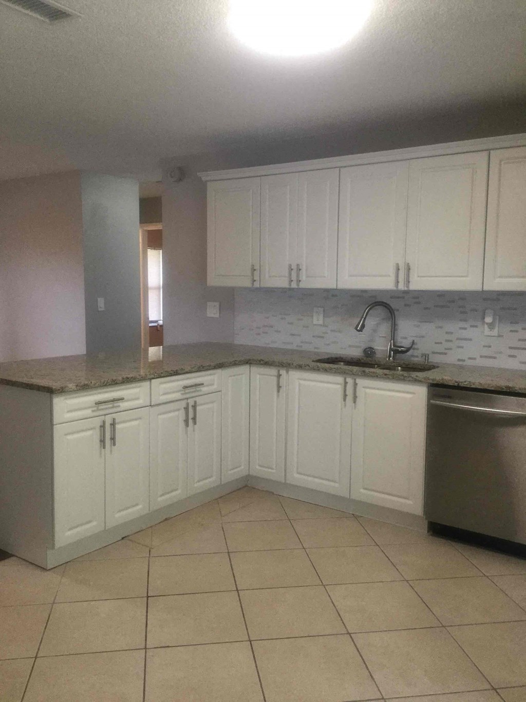 A kitchen with white cabinets and a granite counter top.