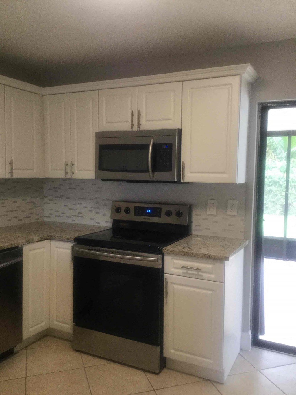 A kitchen with a black stove top oven and white cabinets.