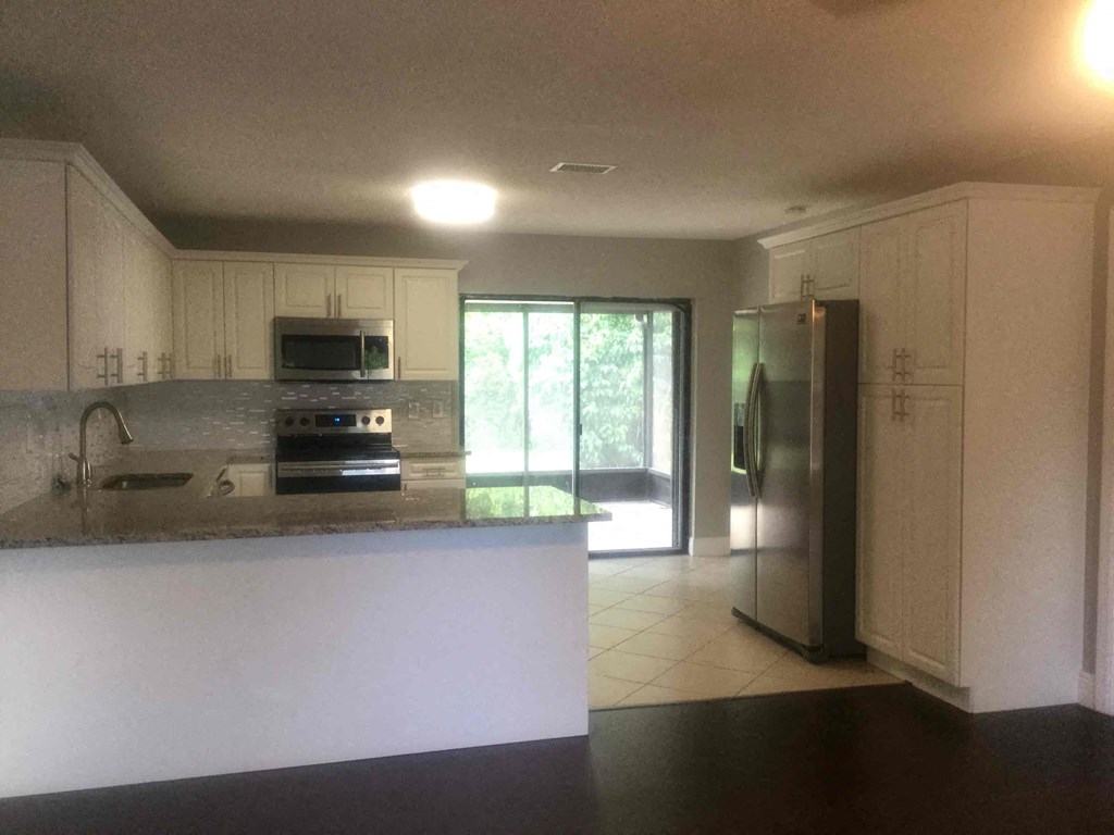 A kitchen with white cabinets and a stainless steel refrigerator.