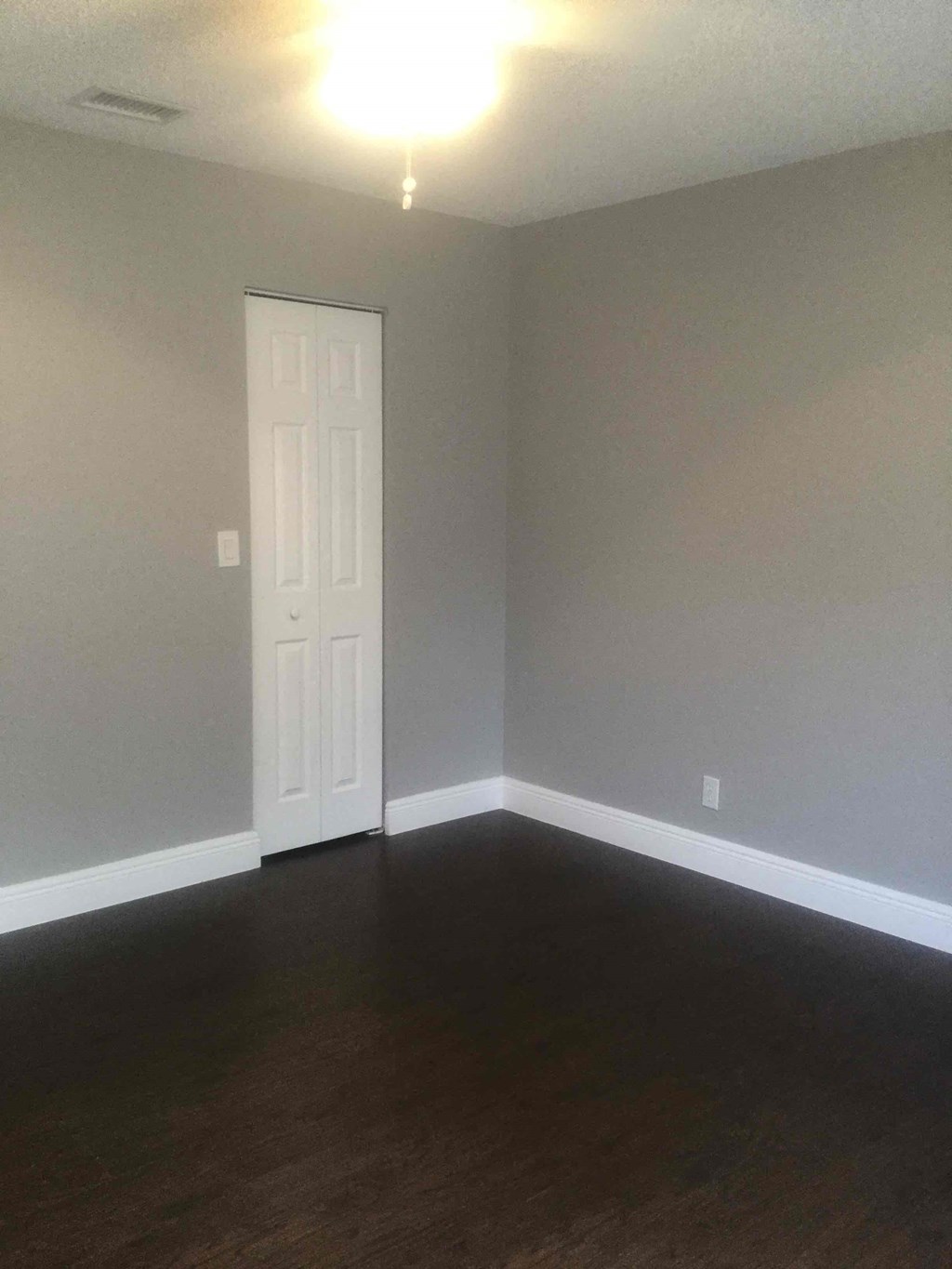 A room with a white door and wooden floor.