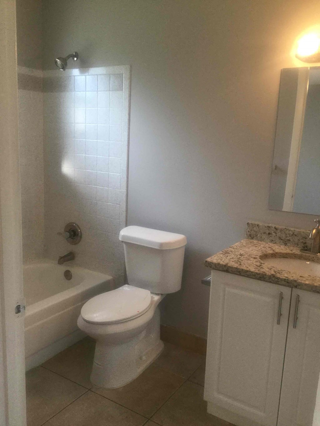 A white toilet sits in a bathroom next to a bathtub.