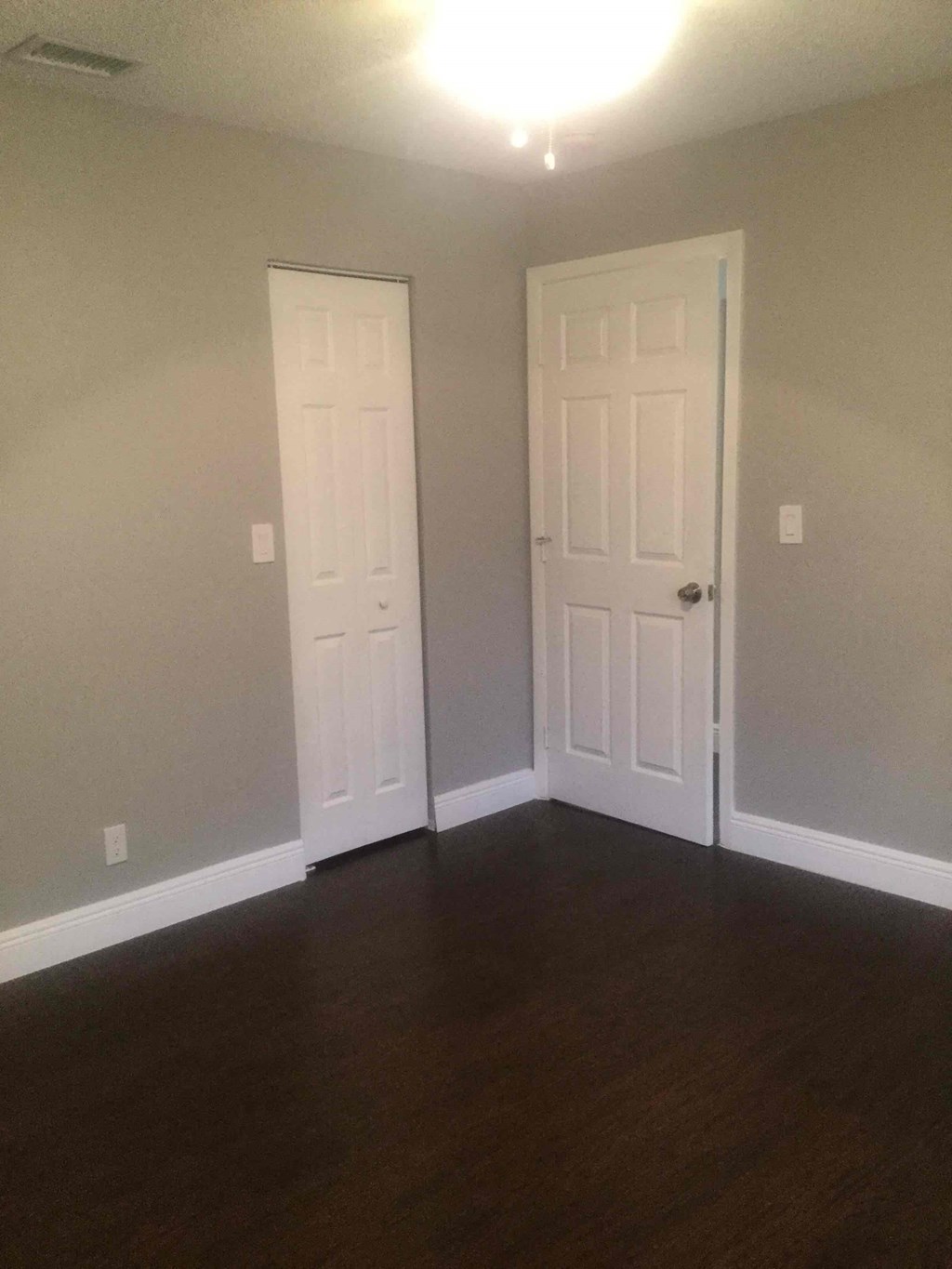 A room with two white doors and wooden floors.