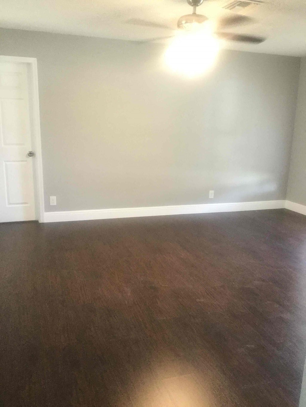 A room with a ceiling fan and wooden flooring.