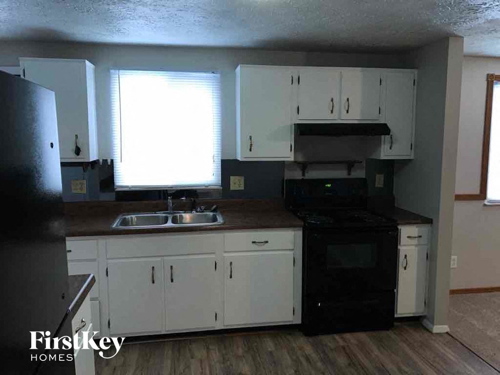 an empty kitchen with white cabinets and black appliances