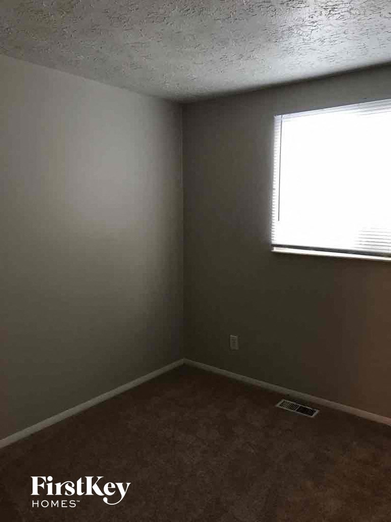 a small room with a window and a brown carpet
