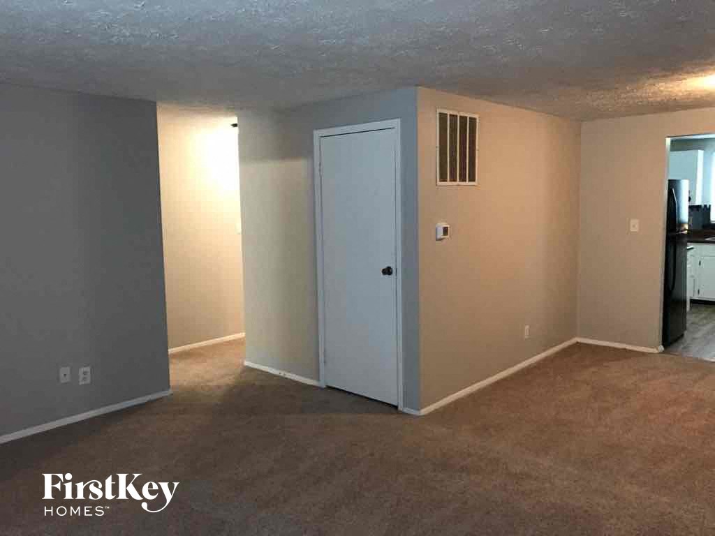 an empty living room with an open door to the kitchen