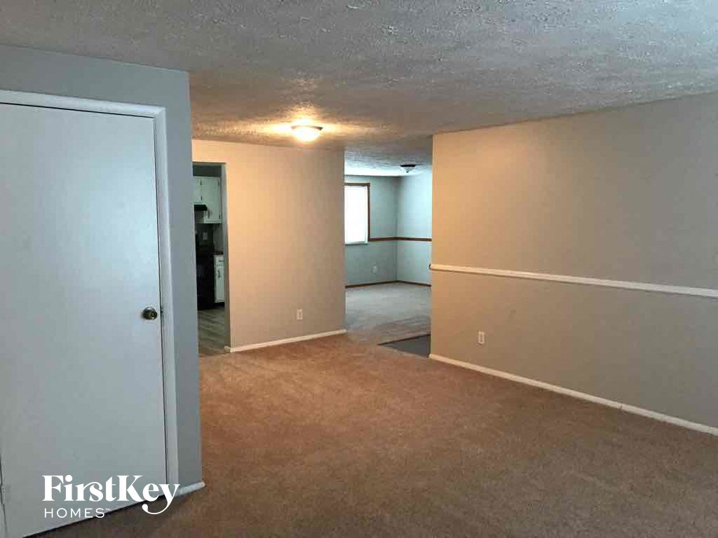 an empty living room and dining room with a door to the kitchen