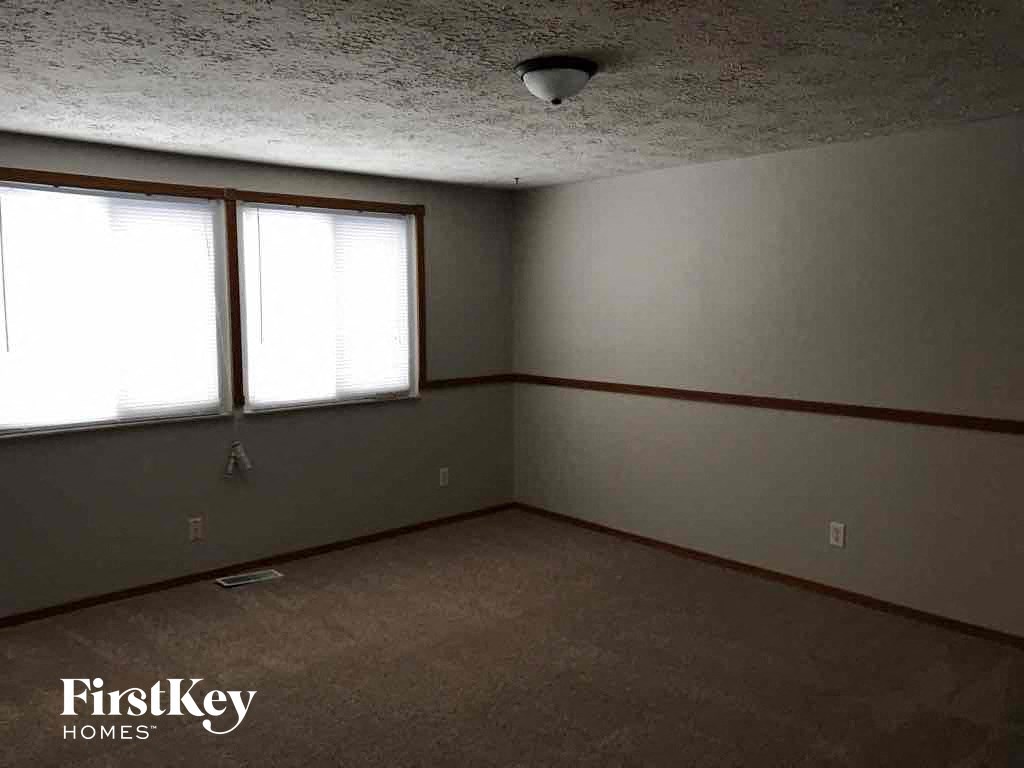 an empty room with two windows and a carpet