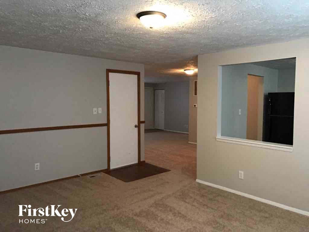 an empty living room and dining room with a door to the bathroom