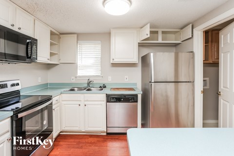 A kitchen with white cabinets and a stainless steel refrigerator.